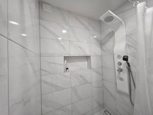 a bathroom with a shower with white tiles at Nemunas Riverside in Kaunas +4 photos