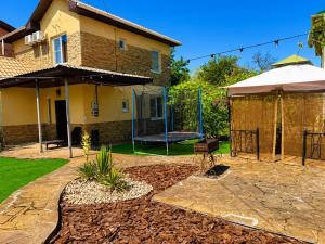 a backyard with a house with a swing at Sunny House Seaside in Zatoka