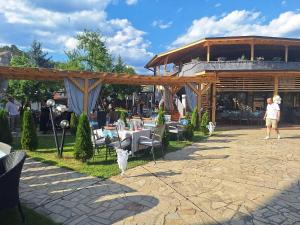 a man standing under a pavilion with tables and chairs at комплекс Иван и Петър in Belitsa