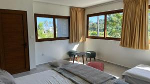 a bedroom with two beds and a table and windows at Villa Lombok Surga Kedua Setangi in Mangsit +109 photos