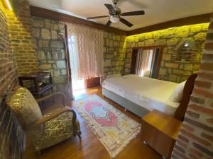 a bedroom with a bed and a stone wall at Qekik Boutique Kazdağları in Arıklı