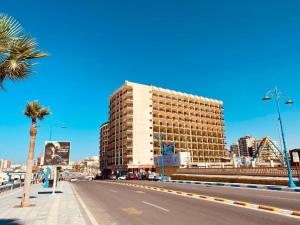 a tall building on a city street with a palm tree at Semiramis Hotel Royal Palace egyptian only in Marsa Matruh