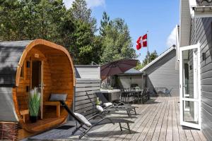 a wooden cabin with chairs and an umbrella on a patio at 0498-Romo-Godthabsvej-29 in Høm