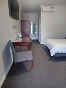 a hotel room with a bed and a desk and a chair at Pastoral Hotel Motel in Port Augusta +1 photo