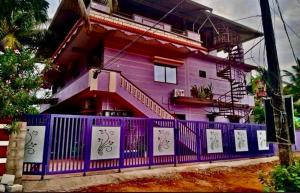 a purple house with a fence in front of it at Anna Miracle Homestay in Kāsarkod
