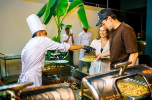 a man handing a plate of food to a woman in a kitchen at Sandy Bliss Mirissa in Mirissa