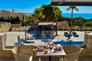 a table with plates of food on it next to the ocean at Quattro Luxury Boutique Suites in Monemvasia