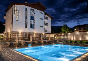 a pool in front of a hotel at night at Family hotel Andreev in Dobrinishte