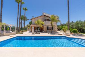 a swimming pool in front of a house with palm trees at Villa Agueda in Muro