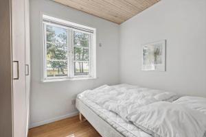a white bedroom with a bed and a window at 0163-Romo-Havnebyvej-5 in Høm