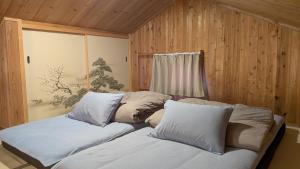 two beds in a room with wooden walls and a window at くまの蔵 Kumanokura inn Storehouse in Shingū +20 photos