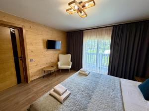 a bedroom with a bed and a chair and a television at Chokolate house in Bukovel
