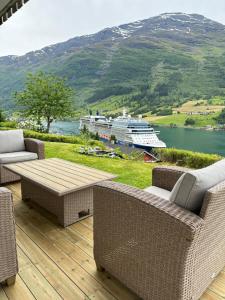 a deck with wicker furniture and a cruise ship in the water at Villa Myklebust in Olden