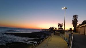 a sunset over the ocean with a sidewalk and a street light at Oeiras Central, near Beach & Public Transport in Oeiras