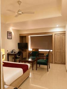 a hotel room with a bed and a desk and a television at May Fair in Mandi