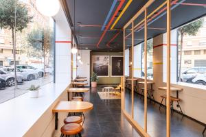 a row of tables and stools in a restaurant with windows at B&B HOTEL Castellón in Castellón de la Plana