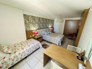 a hotel room with two beds and a table at Betel Flat Executive Praia Boa Viagem in Recife