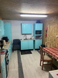 a kitchen with blue cabinets and a table and chairs at The Barn Lodge in Derryounce
