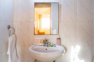 a white bathroom with a sink and a mirror at Rojani Resort in Sām