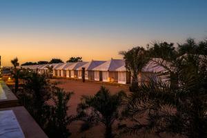 a row of white tents with trees and a sunset at Rojani Resort in Sām