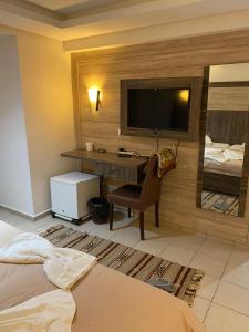 a bedroom with a desk with a television and a bed at Hôtel Matous in Tunis +24 photos