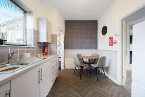a kitchen with white cabinets and a table and chairs at Work Friendly 3 Bed House with Sofa Beds that Sleeps 7 in Fishburn
