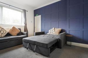 a living room with a couch and a blue wall at Work Friendly 3 Bed House with Sofa Beds that Sleeps 7 in Fishburn