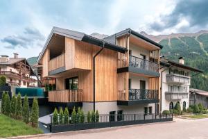 a house with a wooden facade with mountains in the background at Hotel Madonnina Resort And Wellness in Soraga