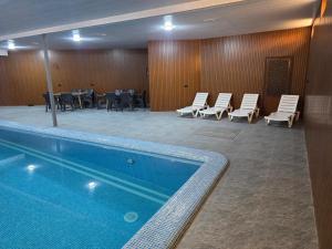 a pool in a hotel room with chairs and tables at MELODIA Guest House in Bukhara