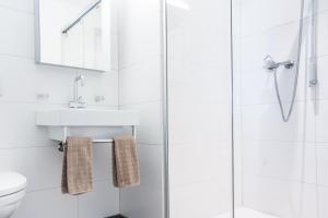 a white bathroom with a sink and a shower at White Apartment in Andermatt
