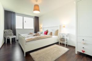 a white bedroom with a bed and a chair at White Apartment in Andermatt