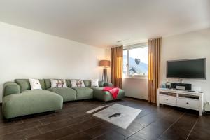 a living room with a green couch and a flat screen tv at White Apartment in Andermatt +12 photos
