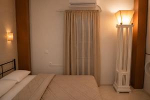 a bedroom with a bed and a lamp and curtains at Siena in Preveza