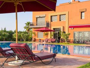 a pool with chairs and umbrellas next to a building at Igrane House - Resort & Spa in Aït Faska