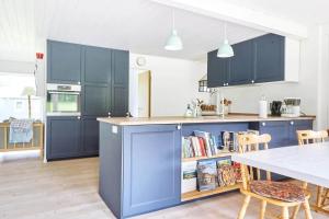 a kitchen with blue cabinets and a table with chairs at 13365-Asnaes-Radyrvej-63 in Asnæs