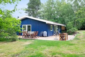 a blue shed with a table and chairs on a deck at 13365-Asnaes-Radyrvej-63 in Asnæs