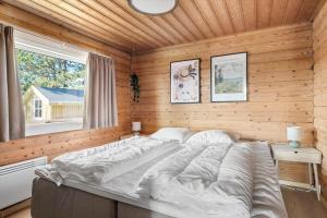 a large bed in a wooden room with a window at 0132-Romo-Kap-Farvel-12 in Høm