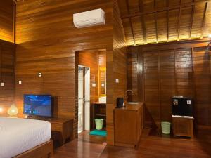 a bedroom with a bed and a television and a bathroom at Bukit Kembang Sari in Bugbug