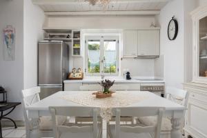 a white kitchen with a table and white chairs at Villa Kohyli by Mediterà in Isterni +56 photos
