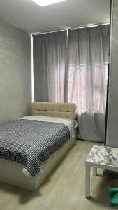 a bedroom with a bed and a window and a table at Studio in Darhan