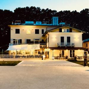 a large white building with tables and chairs in a parking lot at Hotel Butterfly in Torre del Lago Puccini