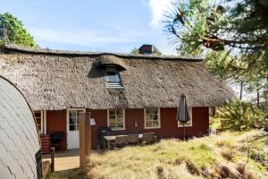 a thatch roofed house with a patio and an umbrella at 0025-Romo-P-J-Manosvej-18 in Høm