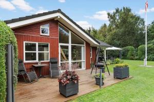a red house with a wooden deck in the yard at LF15149-Farso-Ramshule-49 in Farsø