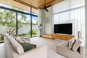 a living room with a flat screen tv and large windows at Botanica Zen by Villacarte in Ban Phru Champa