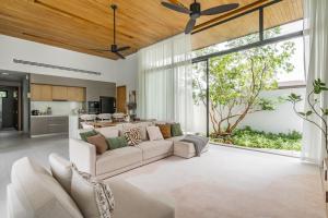 a living room with a couch and a kitchen at Botanica Zen by Villacarte in Ban Phru Champa