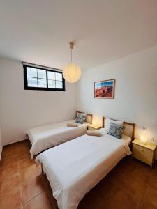 two beds in a room with two windows and two lamps at Surfers Retreat in Corralejo