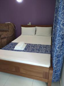 a bed with a wooden frame with a white mattress at Cossy Homes in Mtwapa