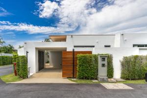 a white house with a wooden door at Botanica Zen by Villacarte in Ban Phru Champa