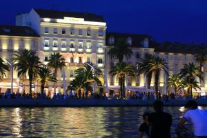 a building with palm trees in front of a body of water at Priuli Luxury Rooms in Split