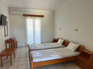a room with two beds and a table and a window at Prokopis Studios in Laganas